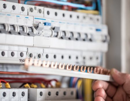 Man, an electrical technician working in a switchboard with fuses. Installation and connection of electrical equipment. Professional with tools in hand. concept of complex work, space for text.