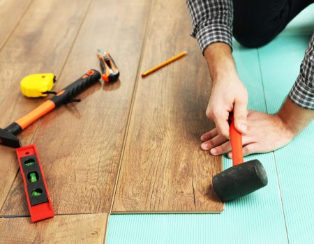 Carpenter worker installing laminate flooring in the room